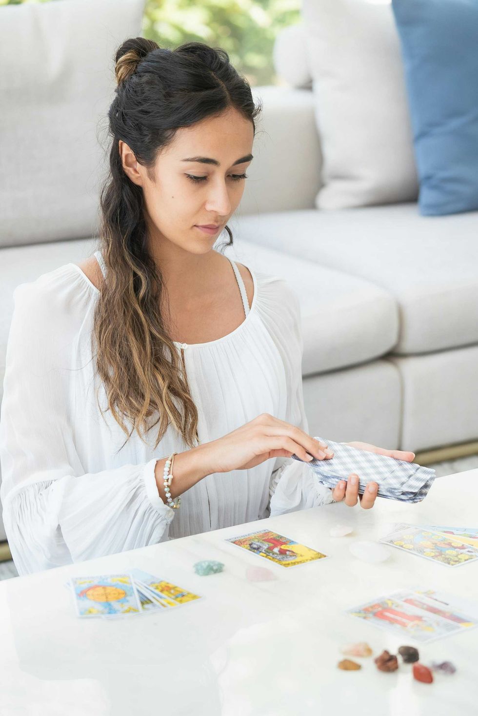 Woman reading tarot cards at a table with crystals.