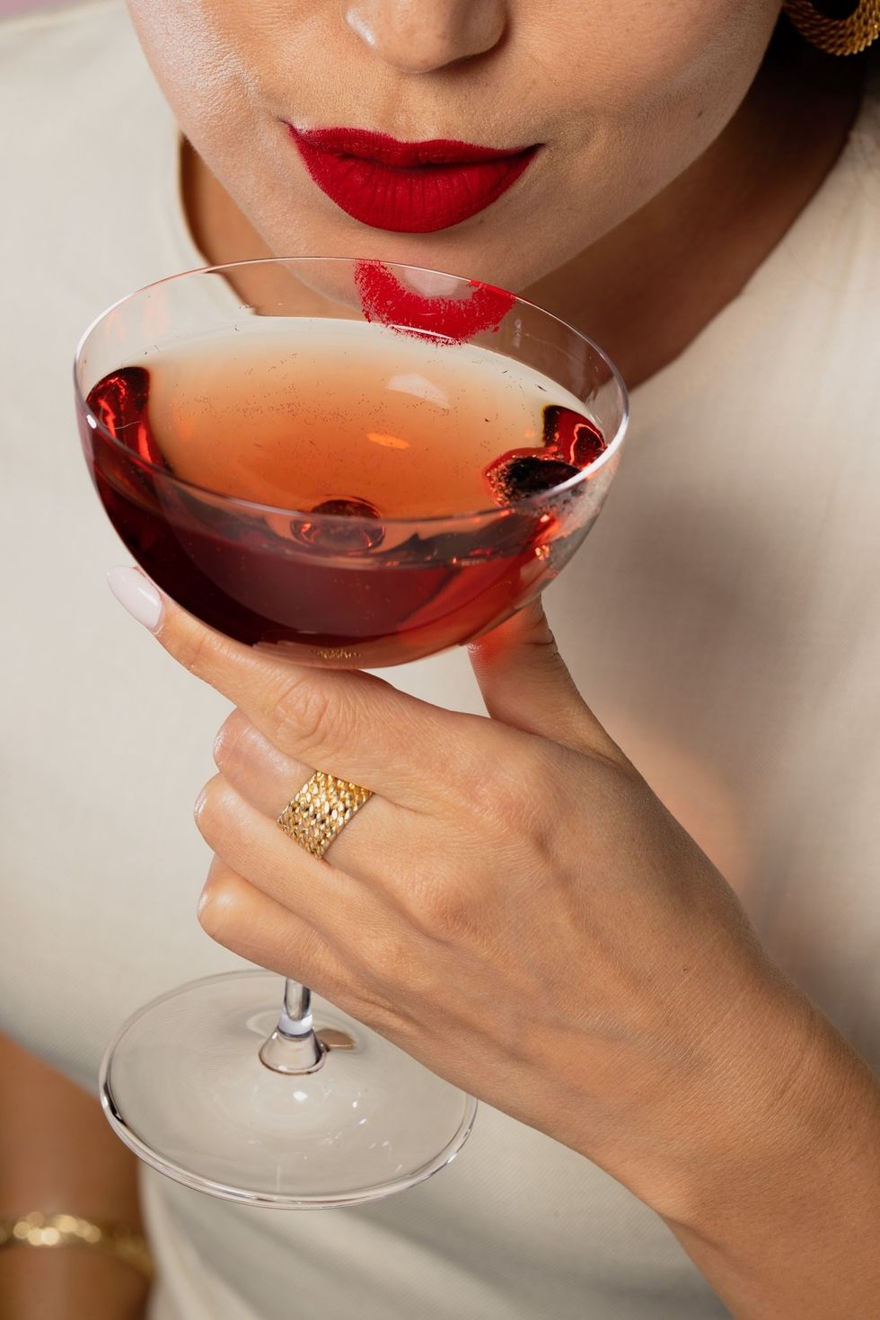 woman sipping a cocktail with red lipstick