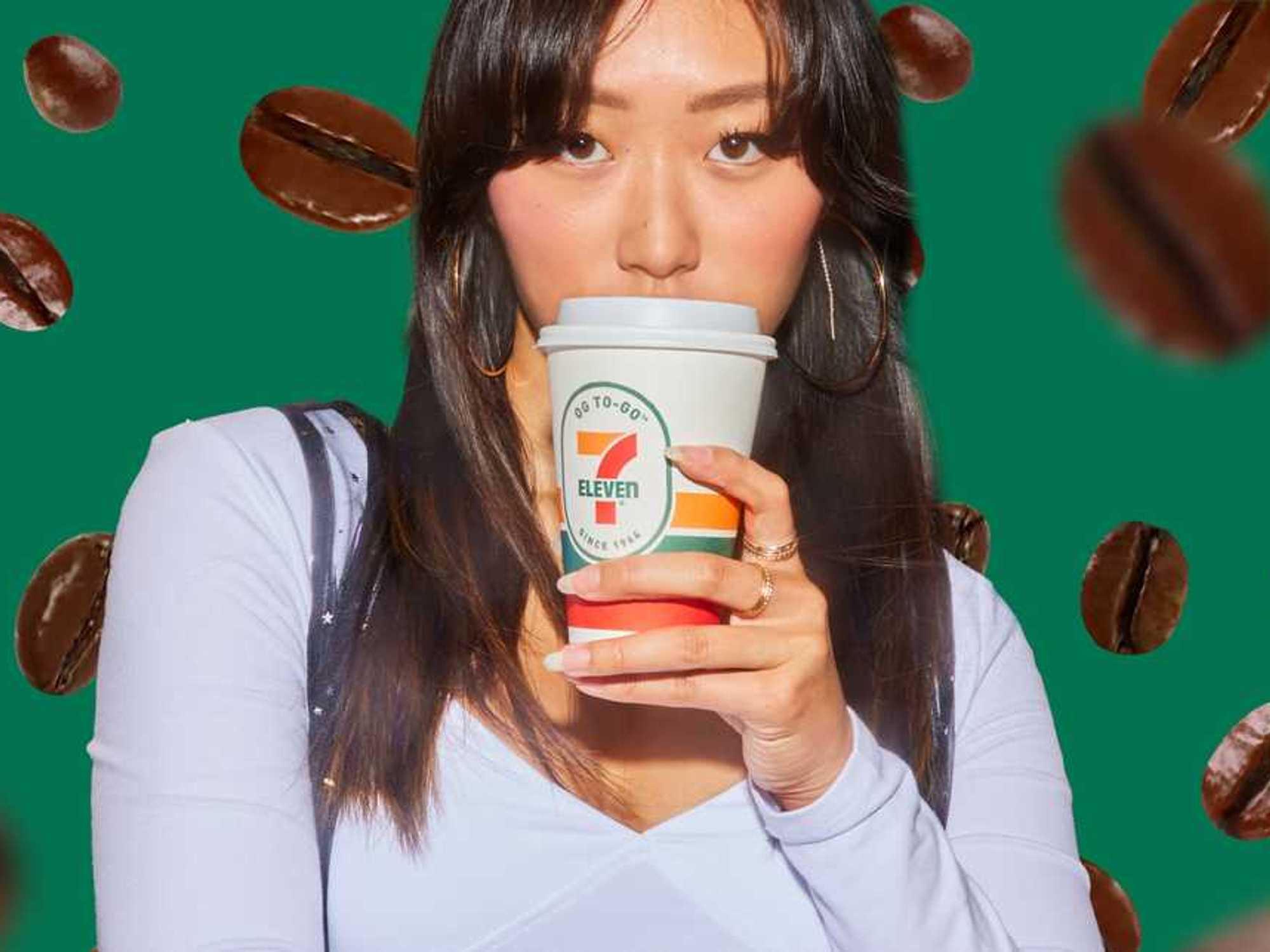 Woman sipping coffee with a 7-Eleven cup, coffee beans in the background.