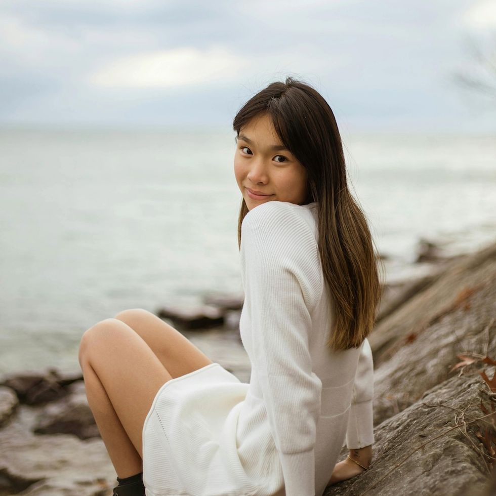 woman sitting by the water on a cloudy day