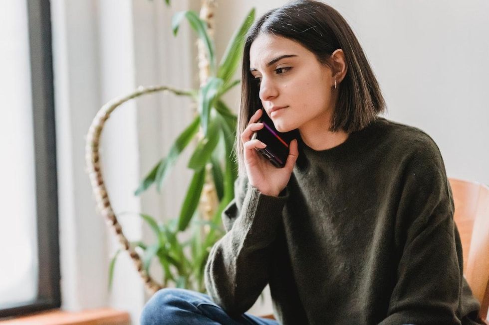woman sitting on her bed on the phone