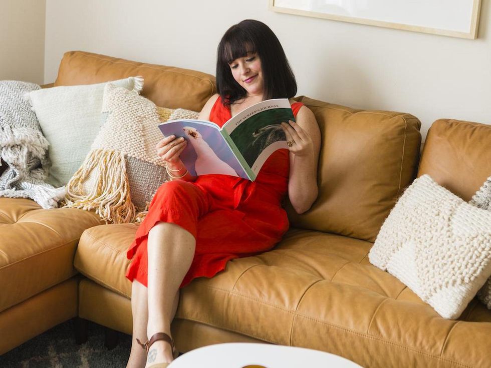 woman sitting on her couch reading a magazine