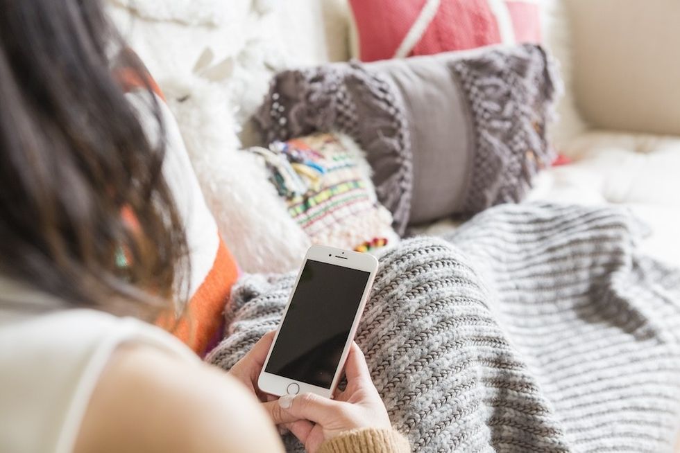 woman sitting on the couch on her phone