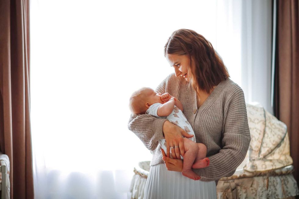 Woman smiling at baby in cozy, light-filled room.