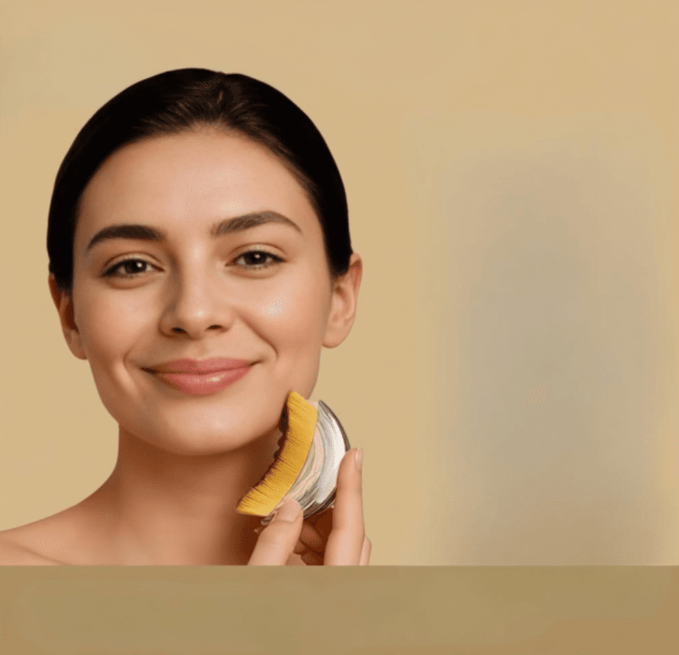 Woman smiling, using a facial brush on beige background.