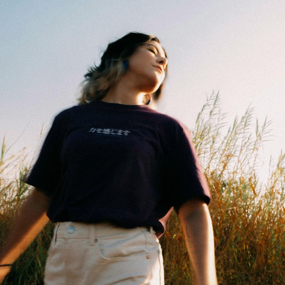 woman standing in a field at golden hour with he eyes closed