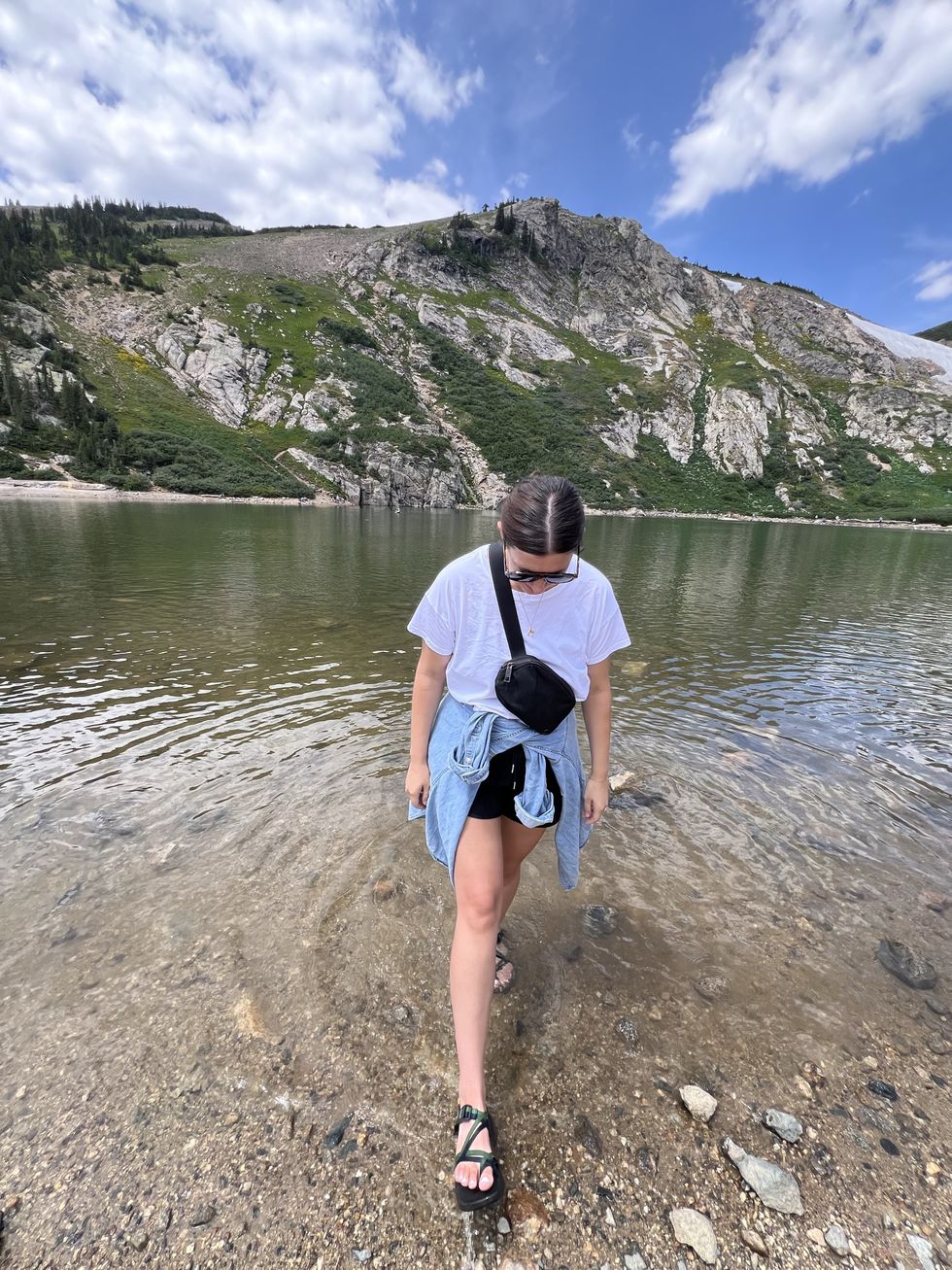 woman standing in the water at the bottom of a mountain