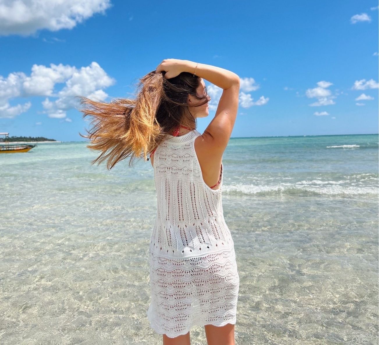 woman standing on the shore of the ocean with the wind blowing in her hair