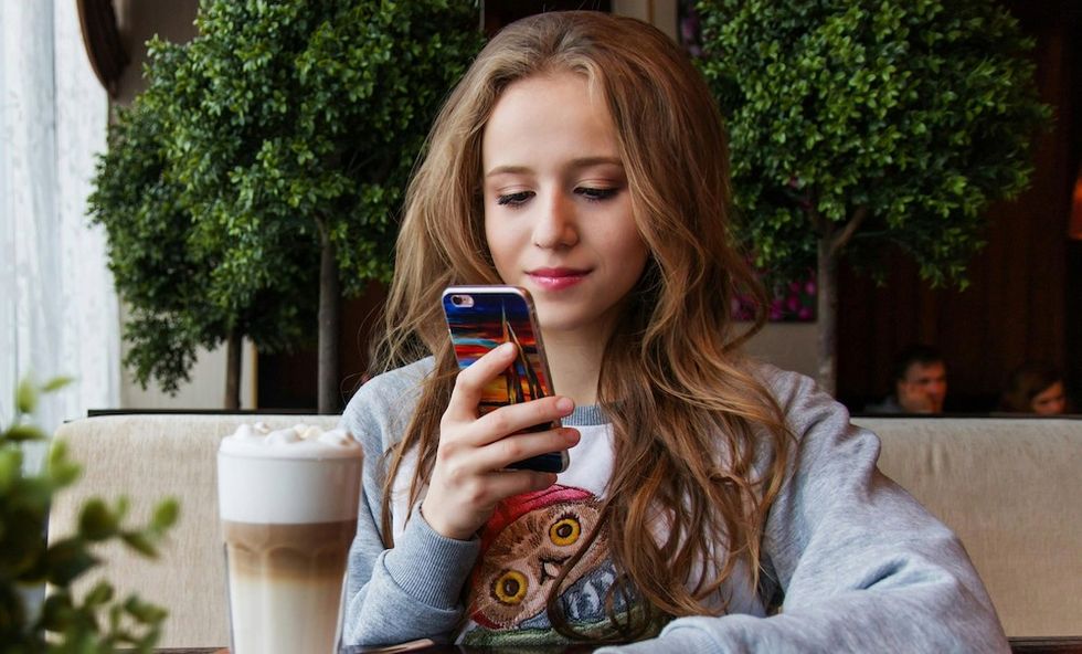 woman taking a picture of her iced latte