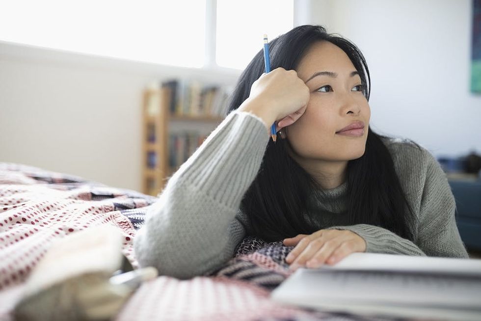 Woman thinking with journal and pencil