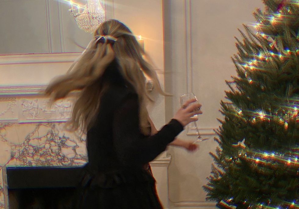 woman twirling with a glass of wine by a christmas tree