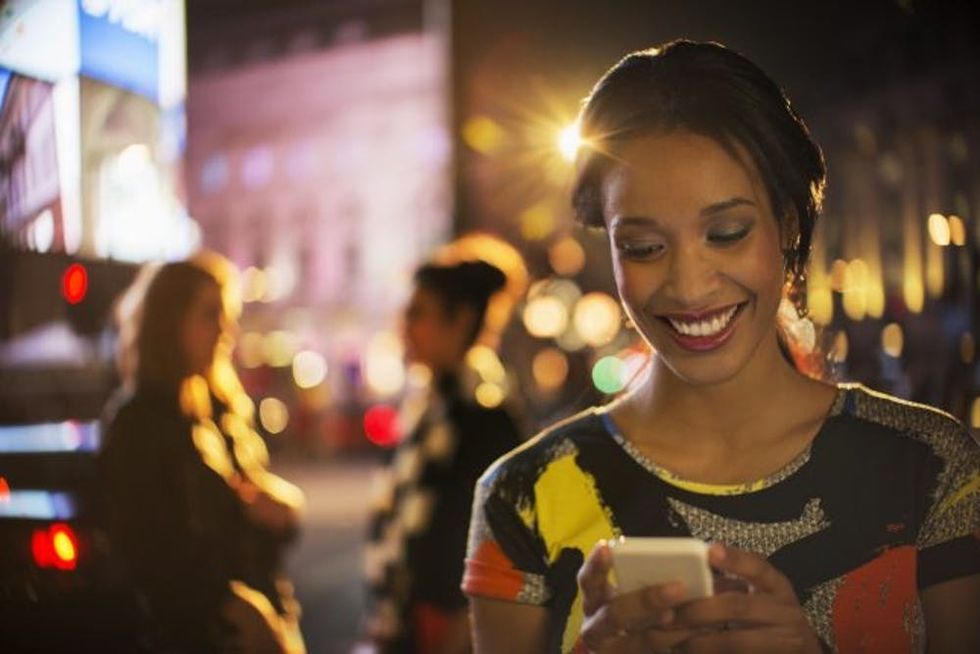 Woman using cell phone on city street at night
