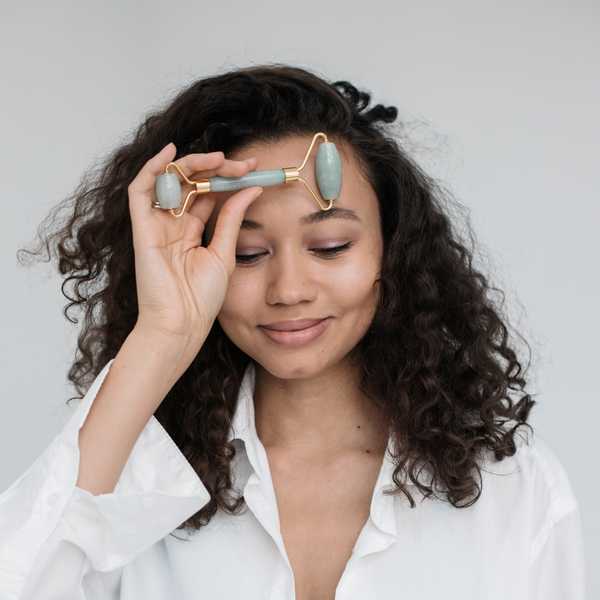 woman using face roller for lymphatic massage