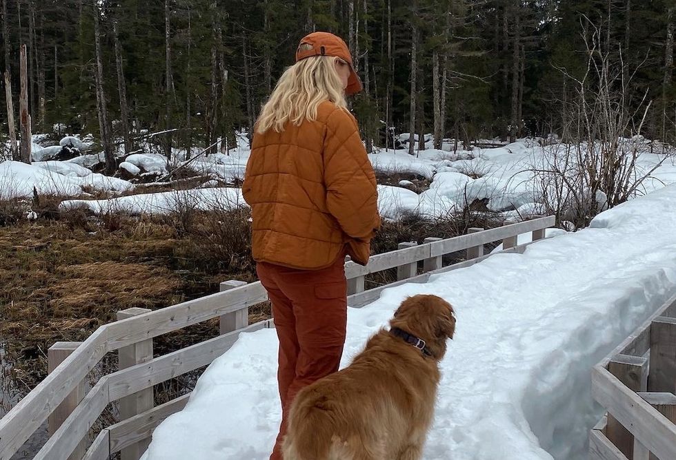 woman walking her golden retriever in the snow