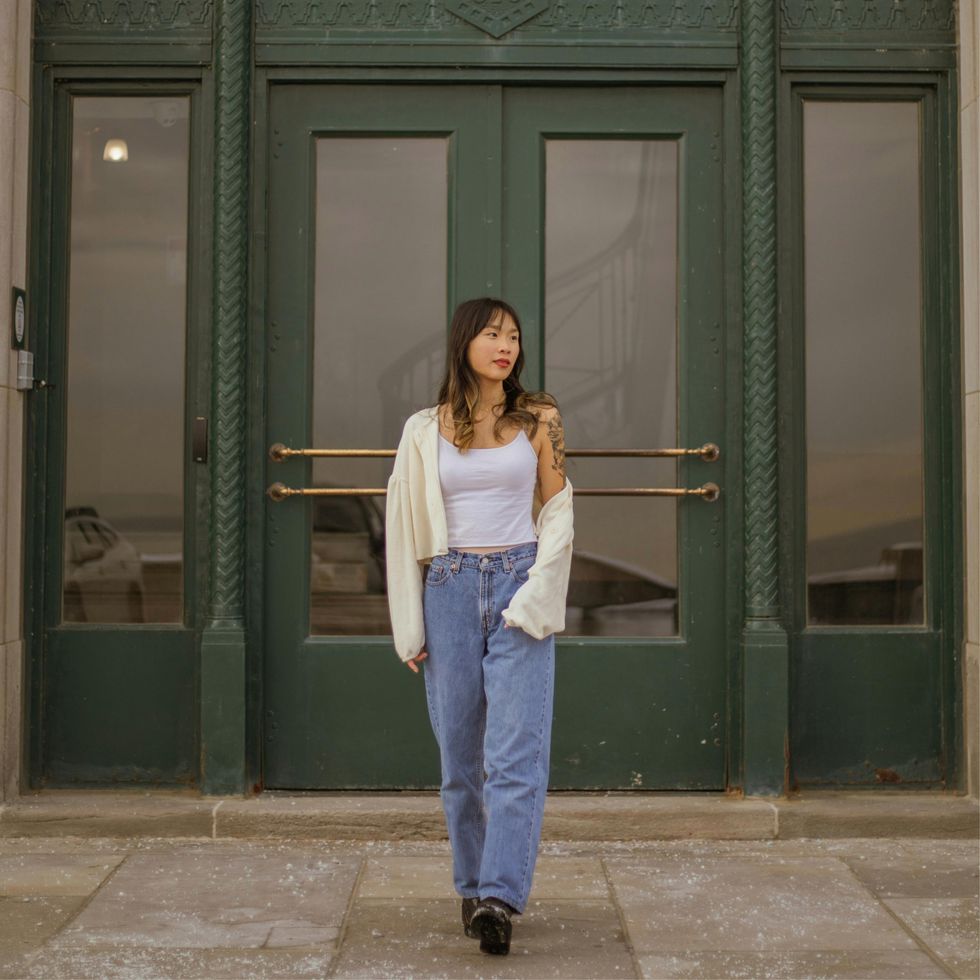 woman walking on the side walk in front a big green door