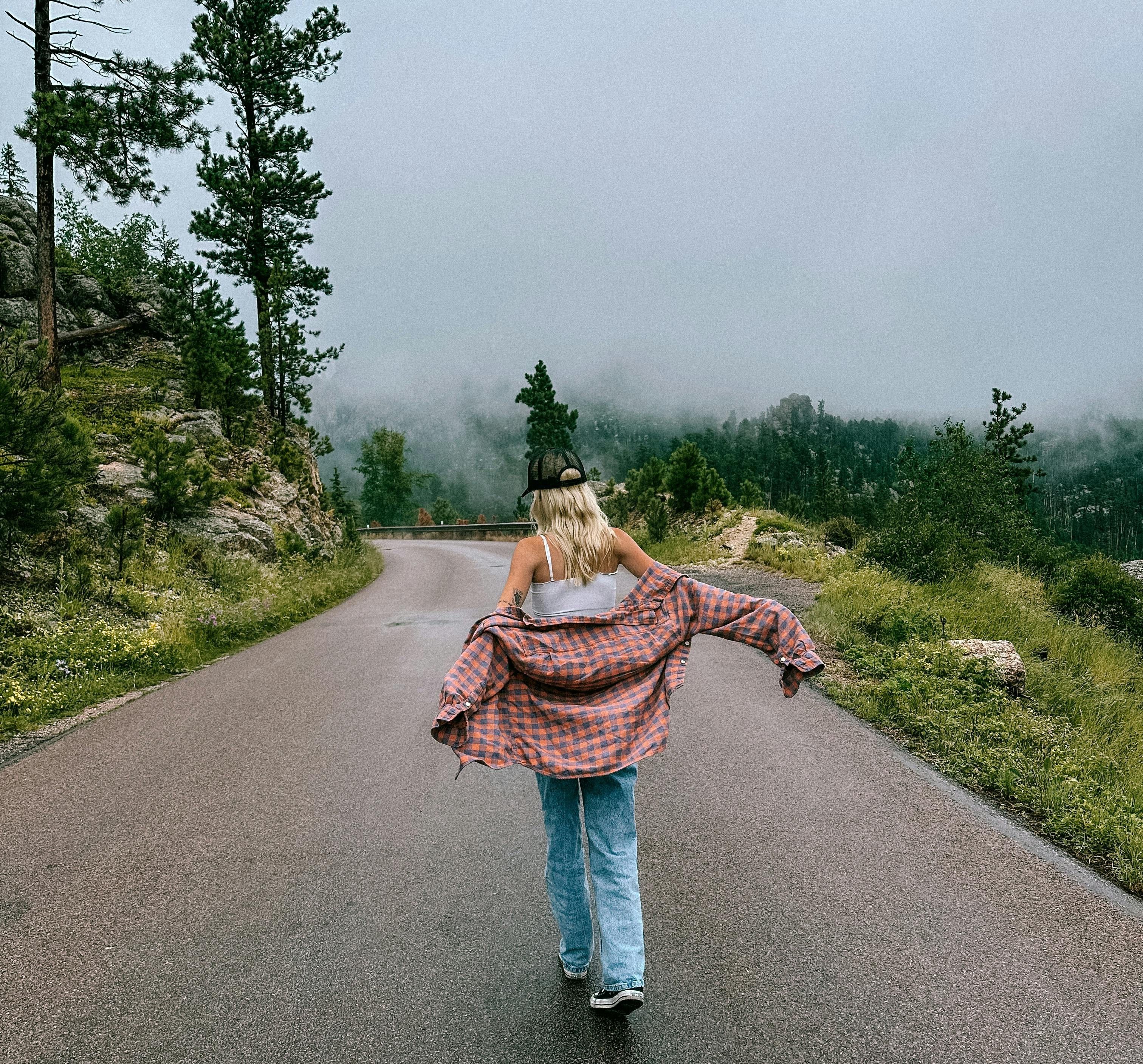 woman walking through the forest on a road in fall