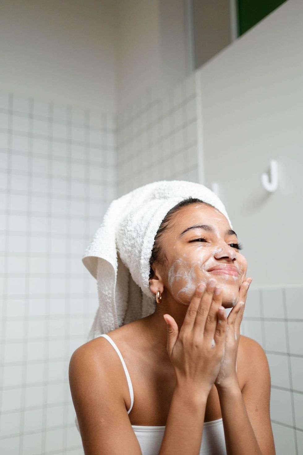 woman washing her face with her hair up in a towel