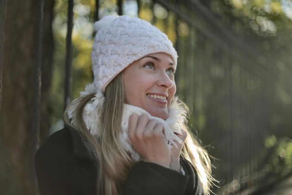 woman wearing a white beanie and a winter coat smiling