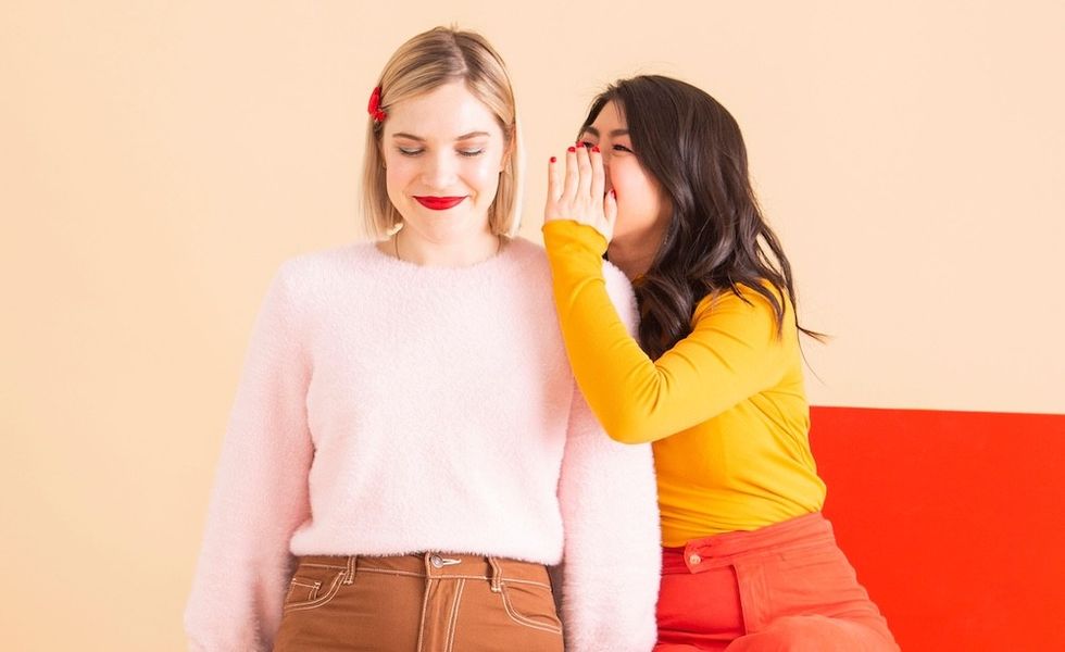 woman whispering in another's ear