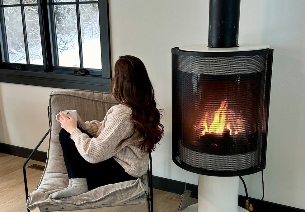 woman with a cup of coffee sitting by a fire