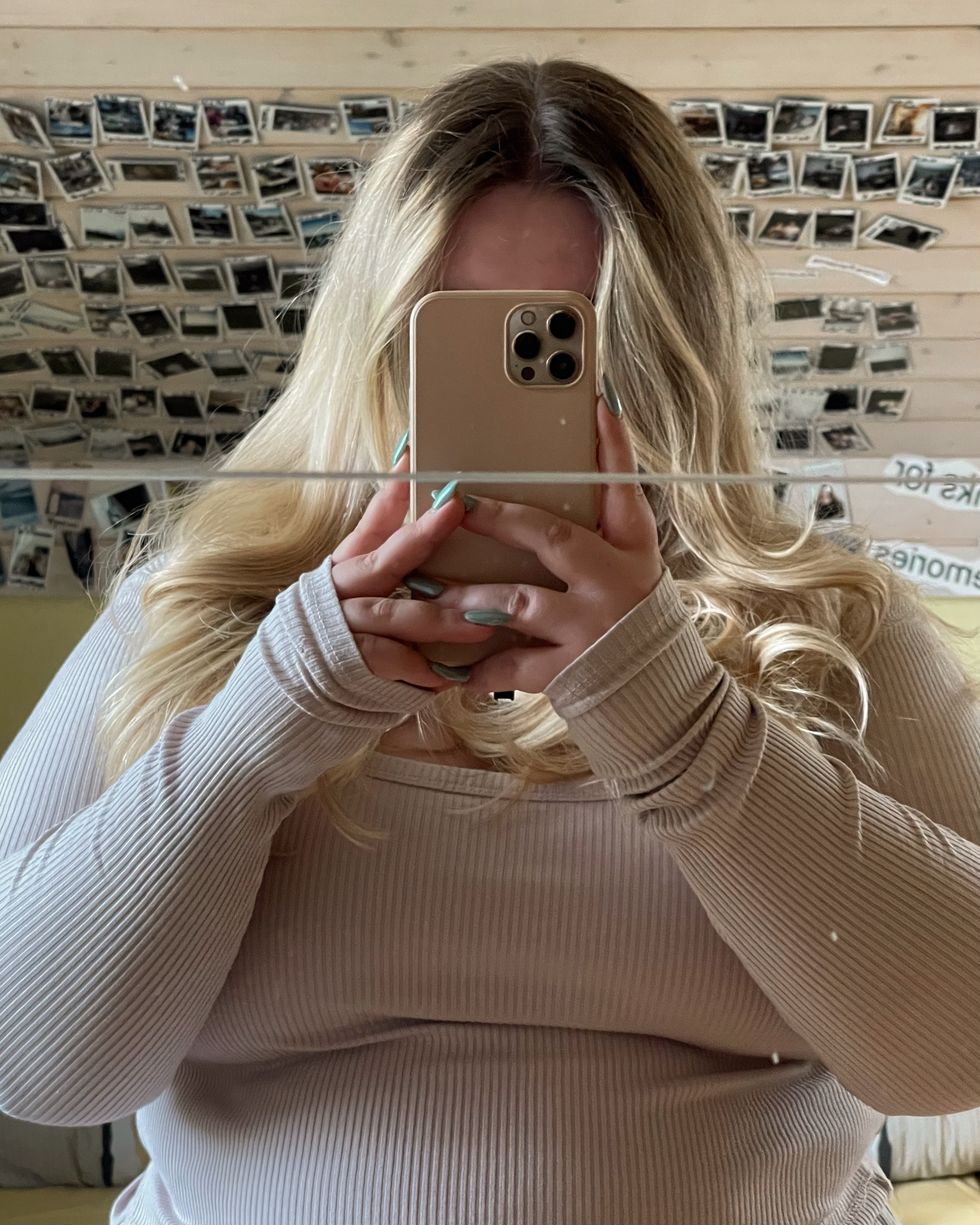 woman with blonde hair taking a mirror selfie