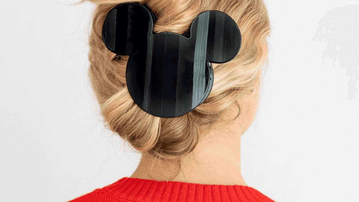 Woman with blonde hair, wearing a Mickey-shaped hair clip, in a red sweater.