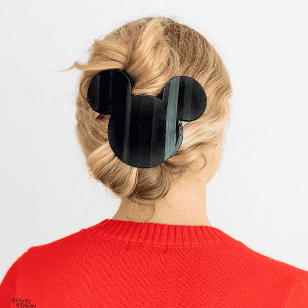 Woman with blonde hair, wearing a Mickey-shaped hair clip, in a red sweater.