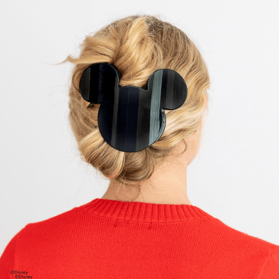 Woman with blonde hair, wearing a Mickey-shaped hair clip, in a red sweater.