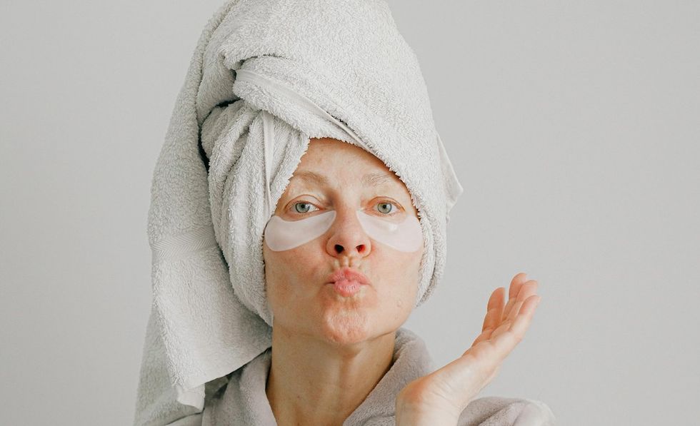 woman with her hair drying in a towel and skincare on her face