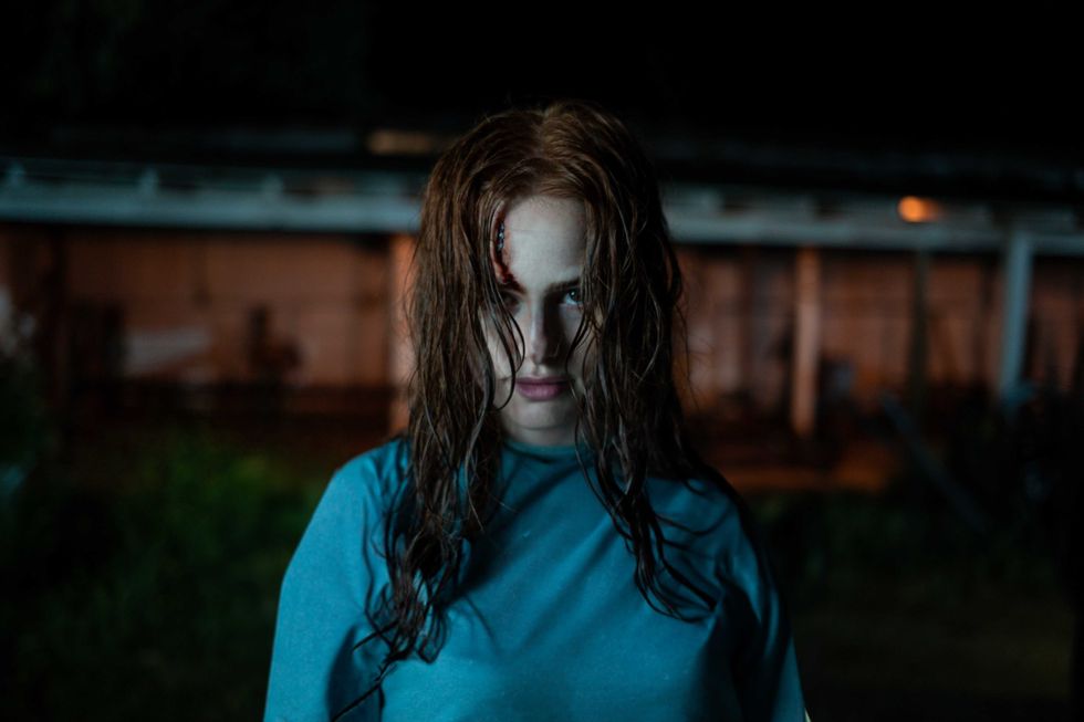 Woman with wet hair and intense gaze standing outside at night.