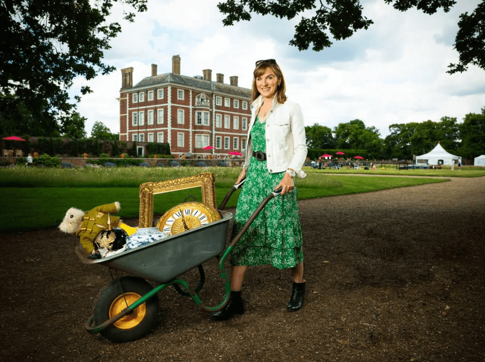 Woman with wheelbarrow of antiques in front of a historic building.