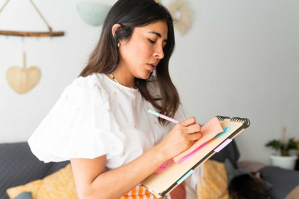 Woman writing on a notebook with colorful sticky notes.