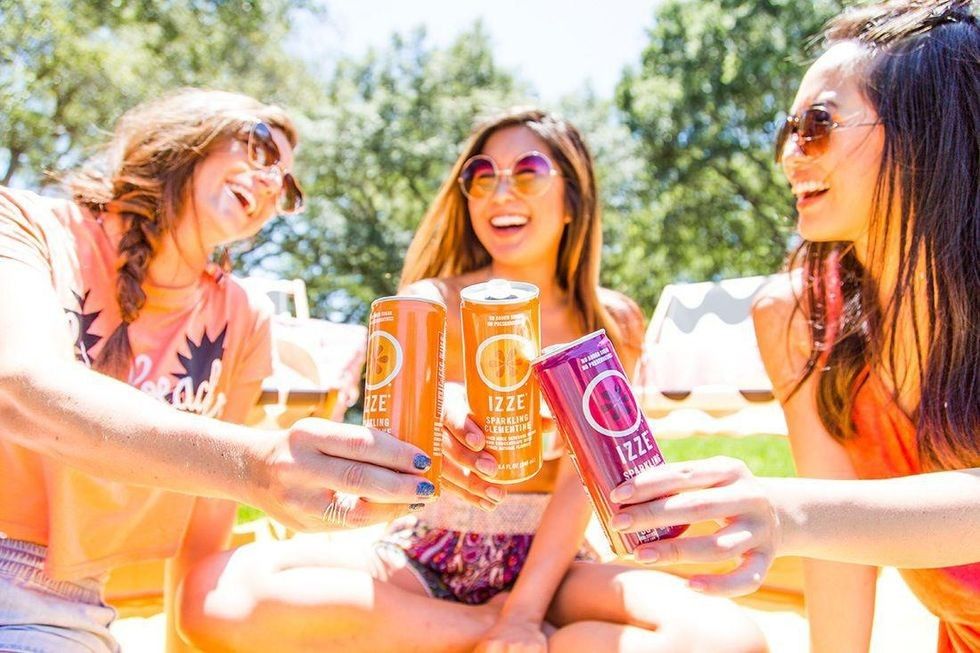 women cheersing their cans of izze