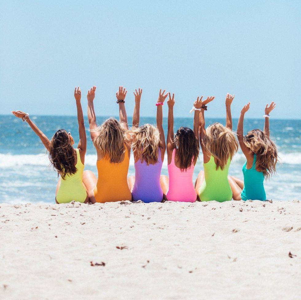 women on a beach in neon bathing suits on vacation