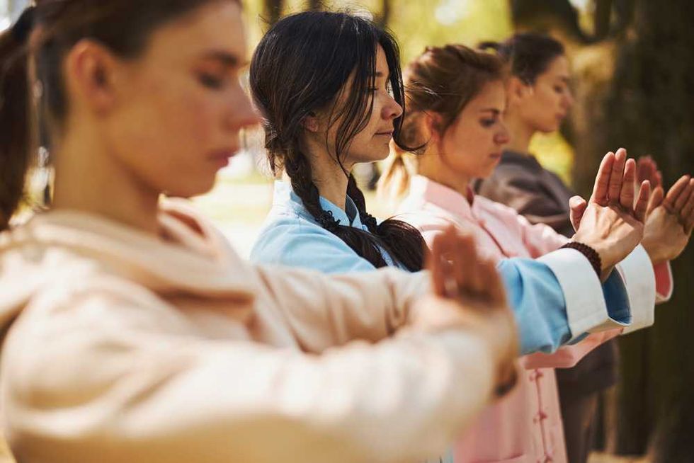 Women practicing meditation or Tai Chi outdoors in peaceful focus.