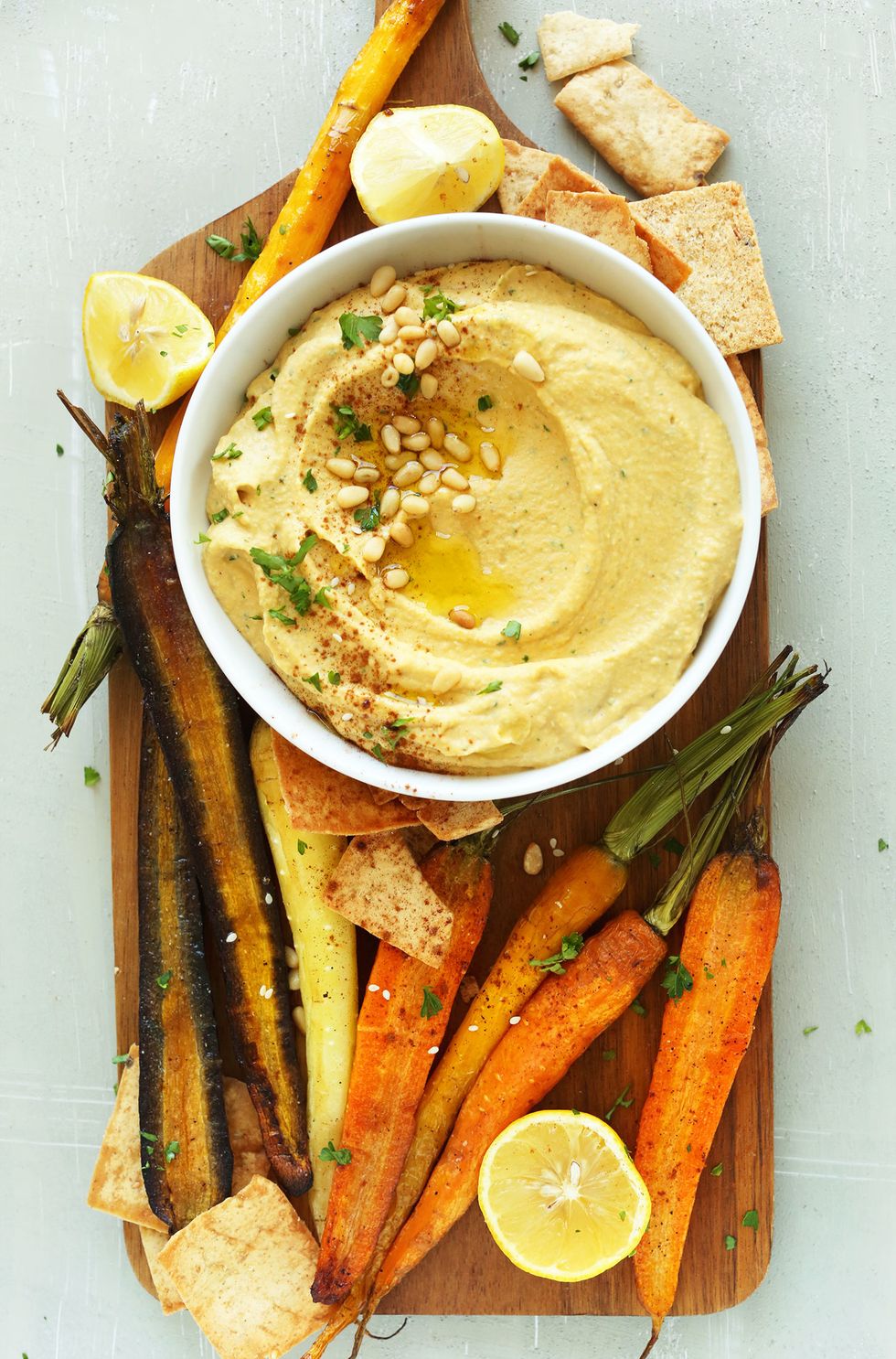 Wood platter with a bowl of gluten-free vegan Butternut Squash Hummus and goodies for dipping