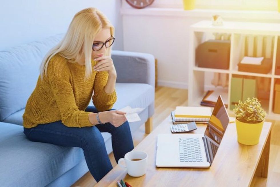 Worried young woman counting bills