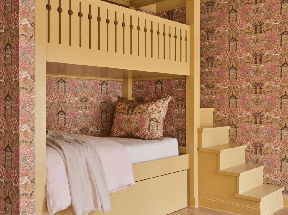 Yellow bunk bed with stairs, floral wallpaper, and pink bedding.