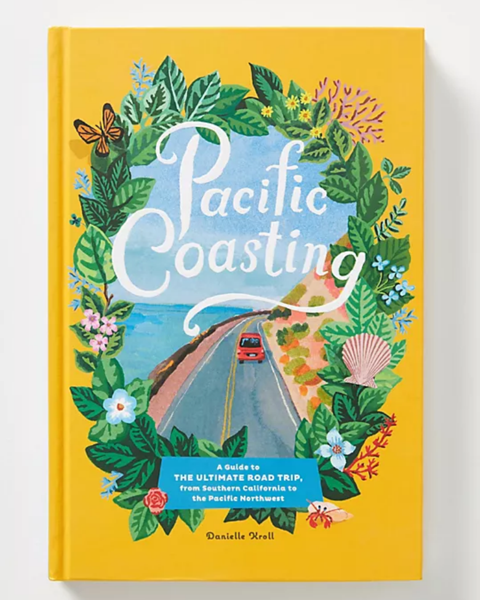 yellow coffee table book with a car on a road framed by a floral wreath