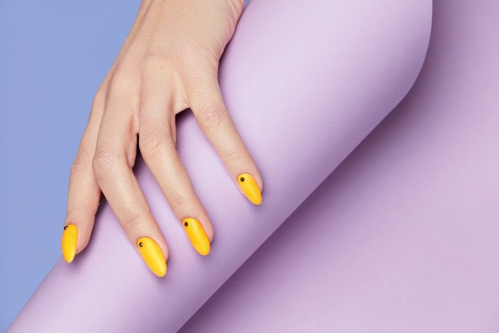 Yellow fingernails on a purple background. 