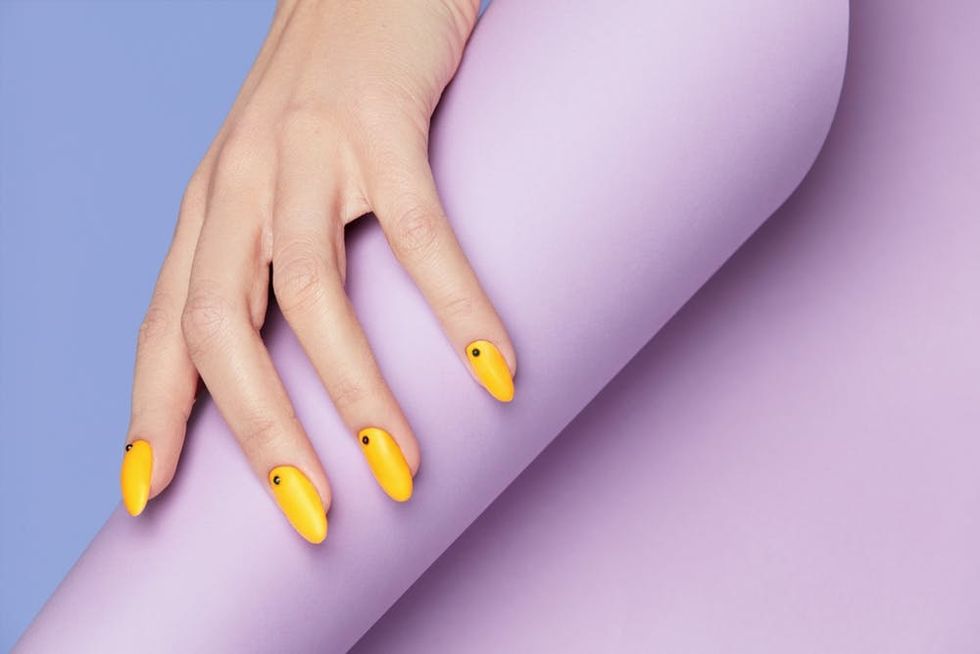Yellow fingernails on a purple background.