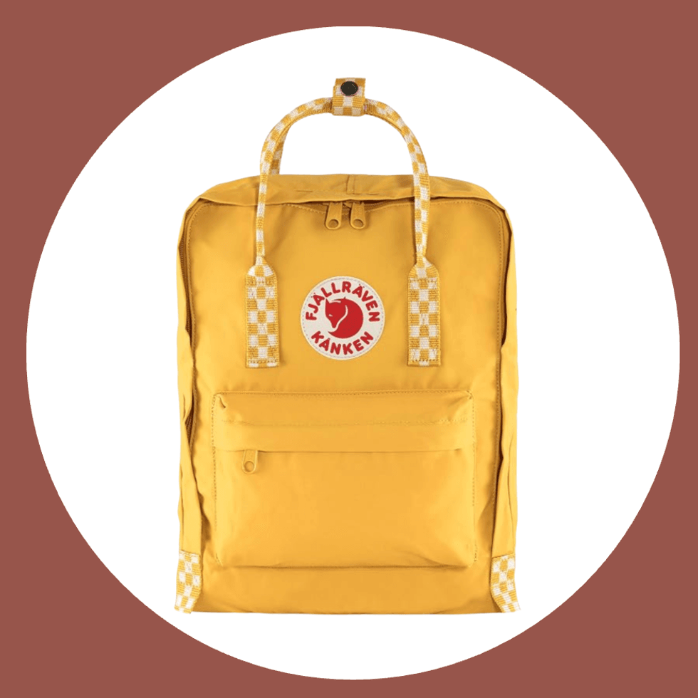 Yellow K\u00e5nken backpack with checkered handles on a circular maroon and white background.