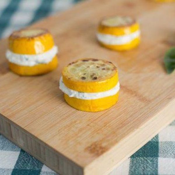 yellow squash slices with ricotta between them on a cutting board and white and teal gingham napkin
