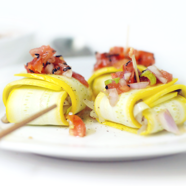 yellow zucchini ravioli with veggies on a white plate