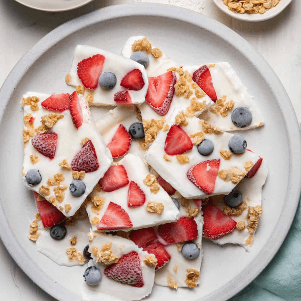 Yogurt bark with strawberries, blueberries, and granola on a white plate.