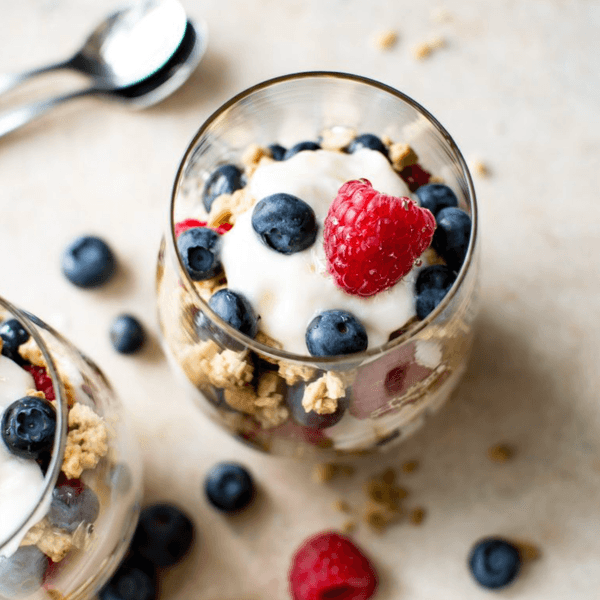 Yogurt parfait with blueberries, raspberries, and granola in glass cups.