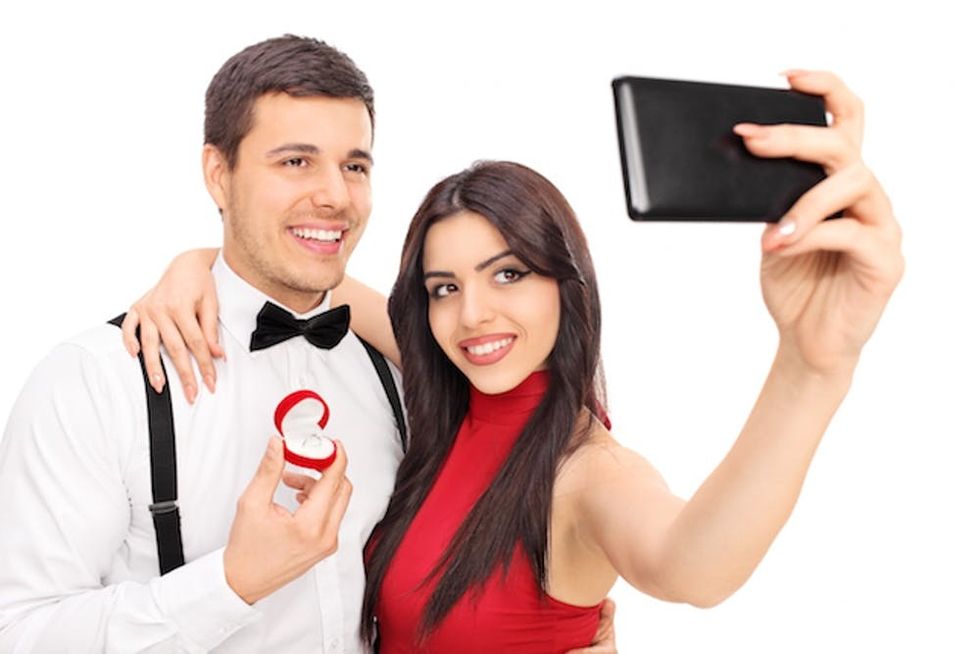 Young couple taking selfie with their engagement ring isolated on white background