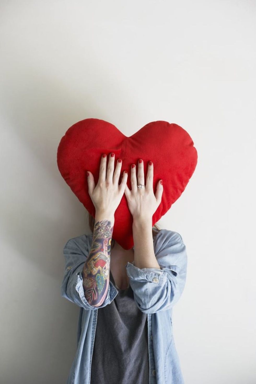 Young woman holding heart-shaped pillow to face