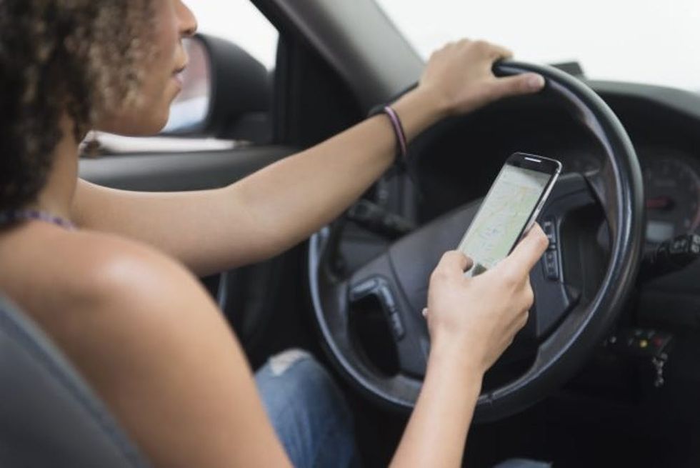 Young woman texting while driving car